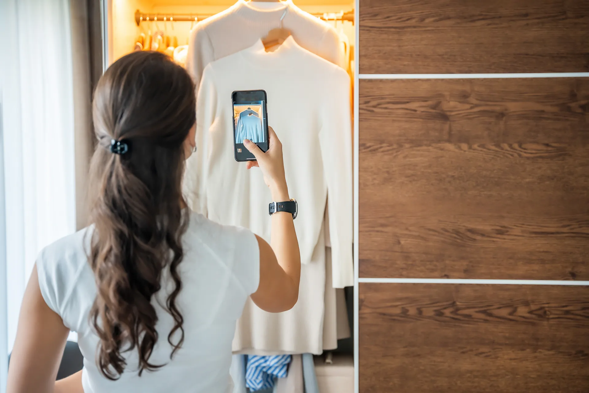 Seller photographing a white dress in her wardrobe to list on Newish