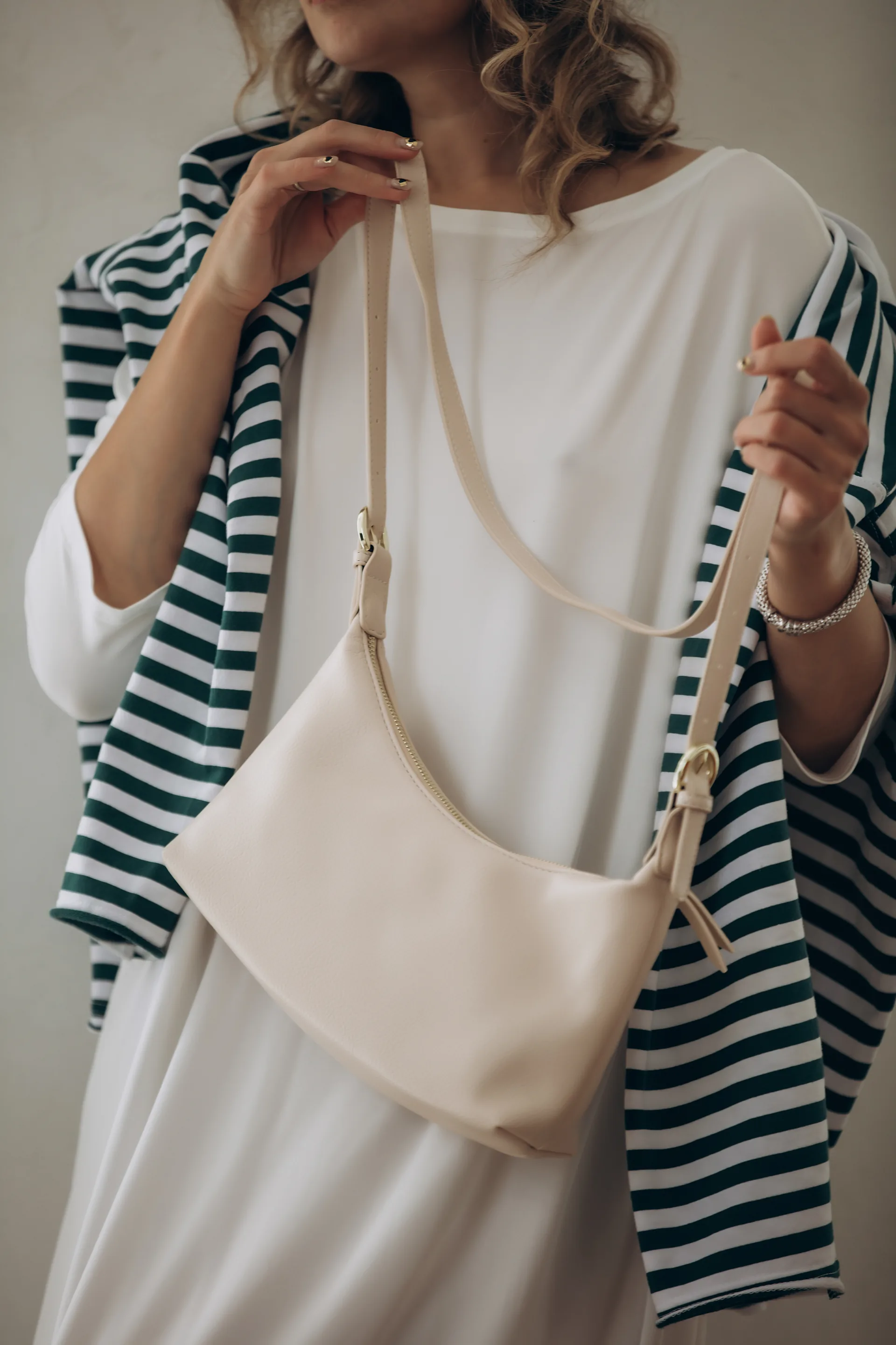 Woman in white dress with striped jacket holding a cream handbag